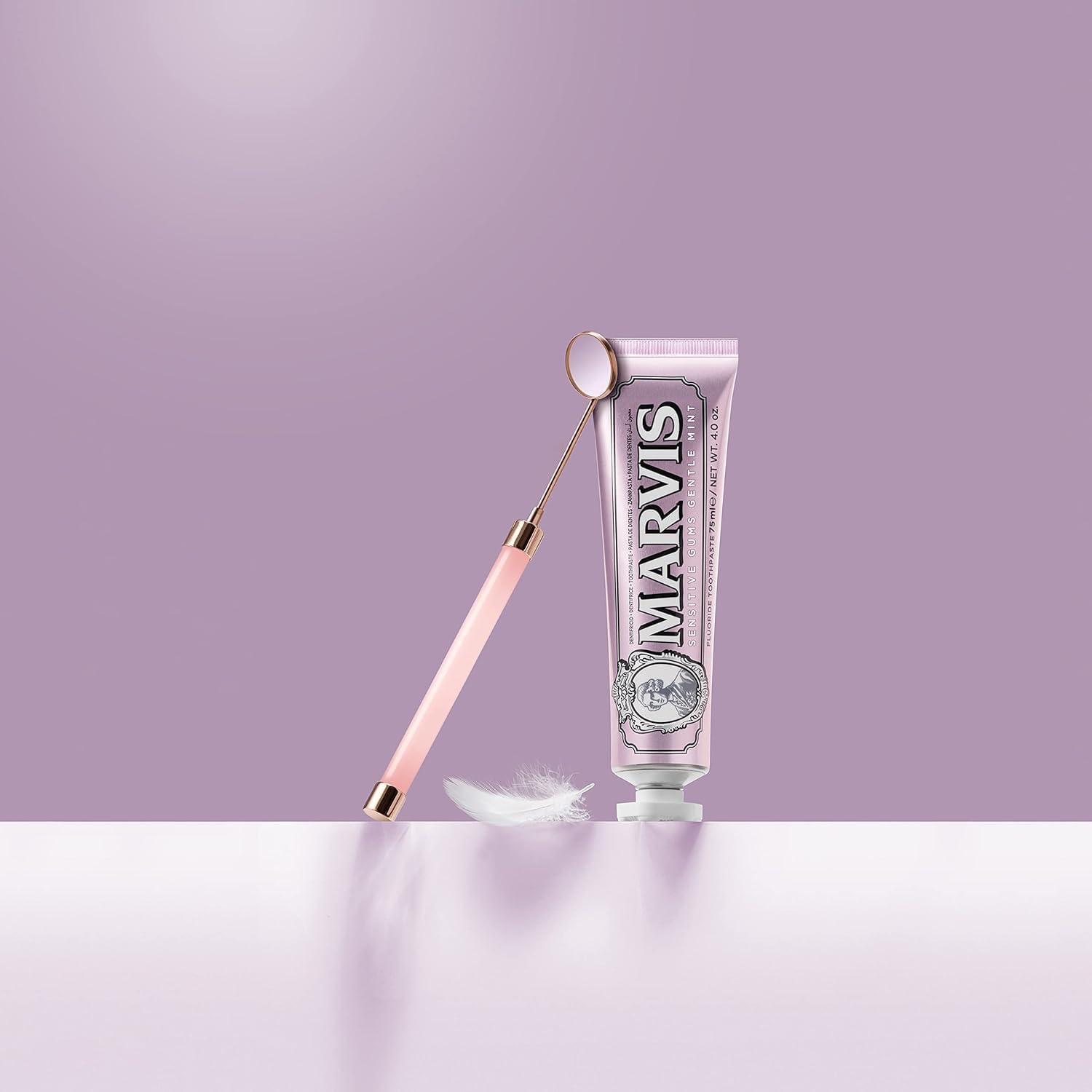 Marvis toothpaste tube with a pink applicator on a light purple background