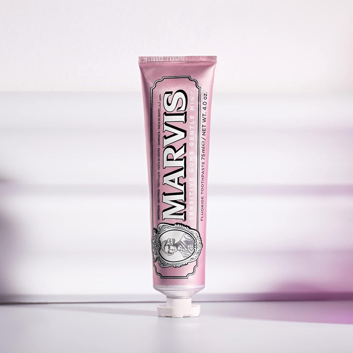 Pink toothpaste tube with 'Marvis' branding on a light purple background
