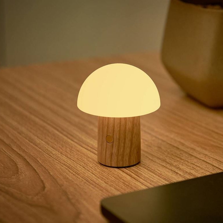 Mushroom-shaped lamp on a wooden surface with a laptop in the background