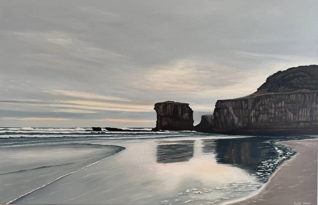 Beach scene with cliffs and ocean under a cloudy sky