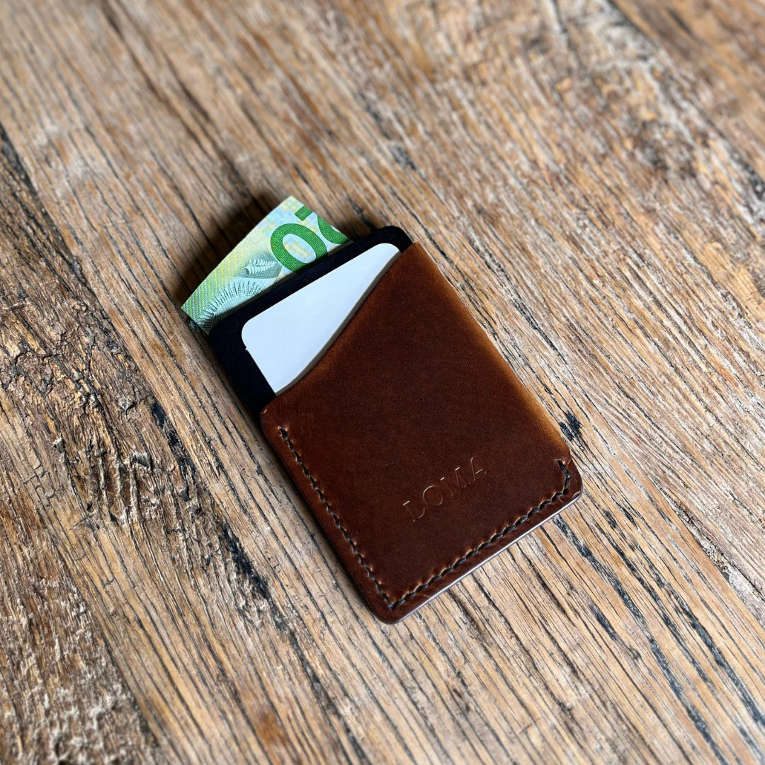 Brown leather wallet with money and cards on a wooden surface