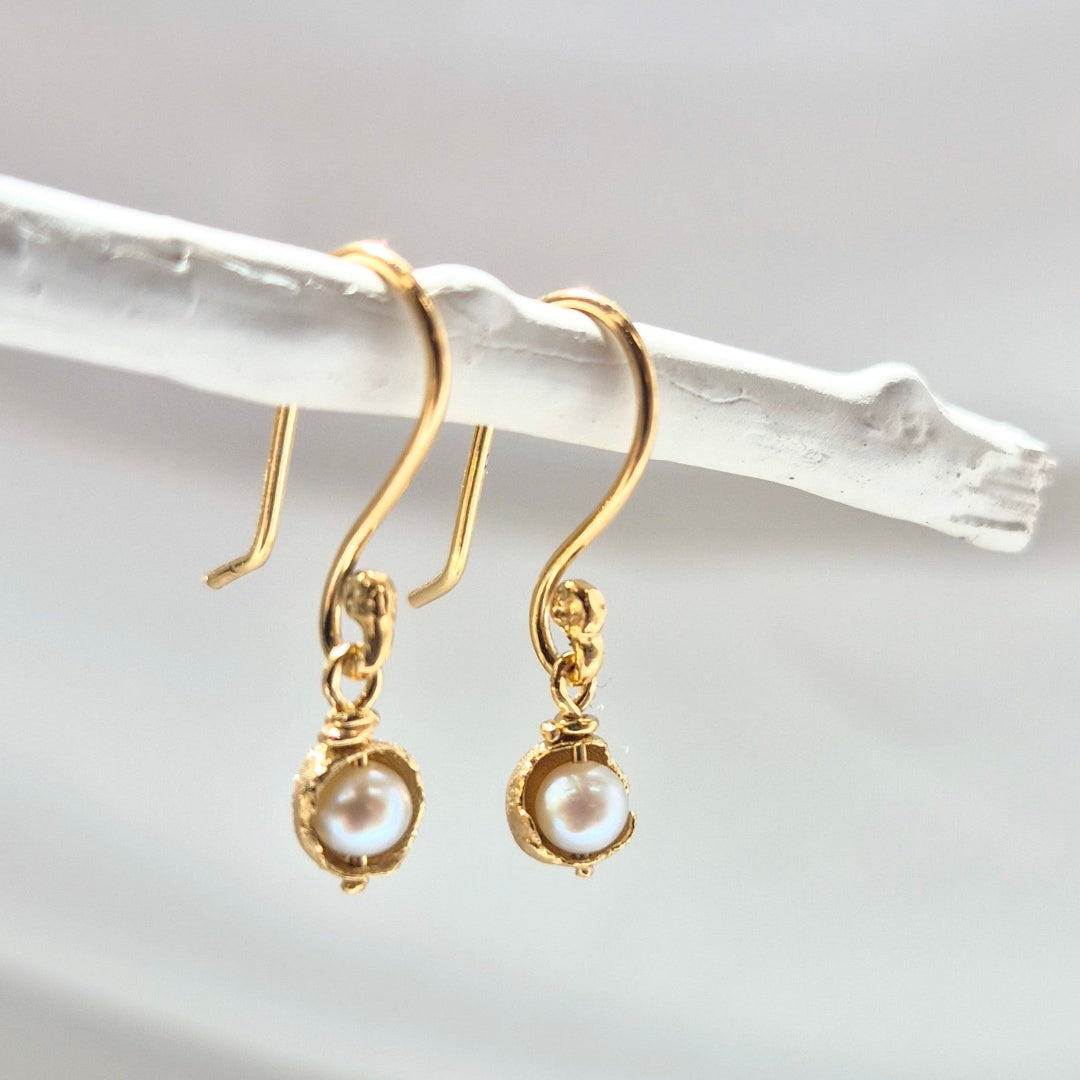 Gold earrings with pearl drops on a white background