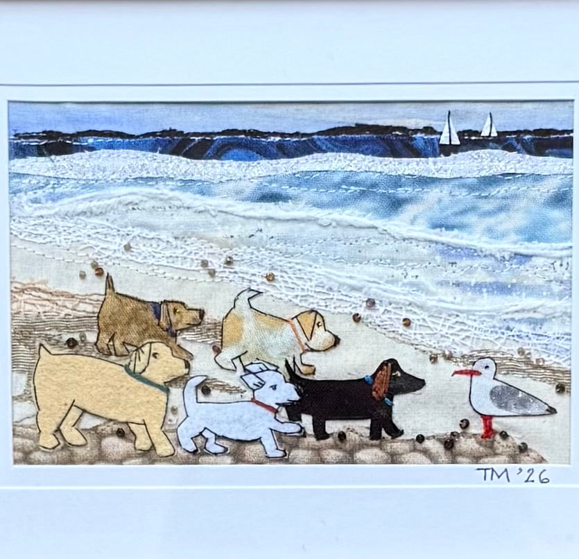 A colourful beach scene textile artwork with a 5 puppies and a seagull.
