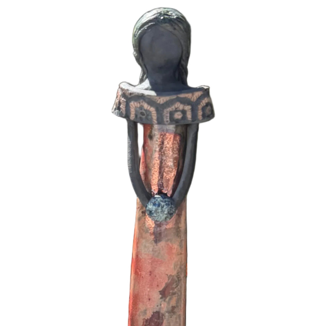 Close up view of a tall lady ceramic figure with a shiny copper glazed dress with patterned collar holding a bouquet, photographed against a white background.