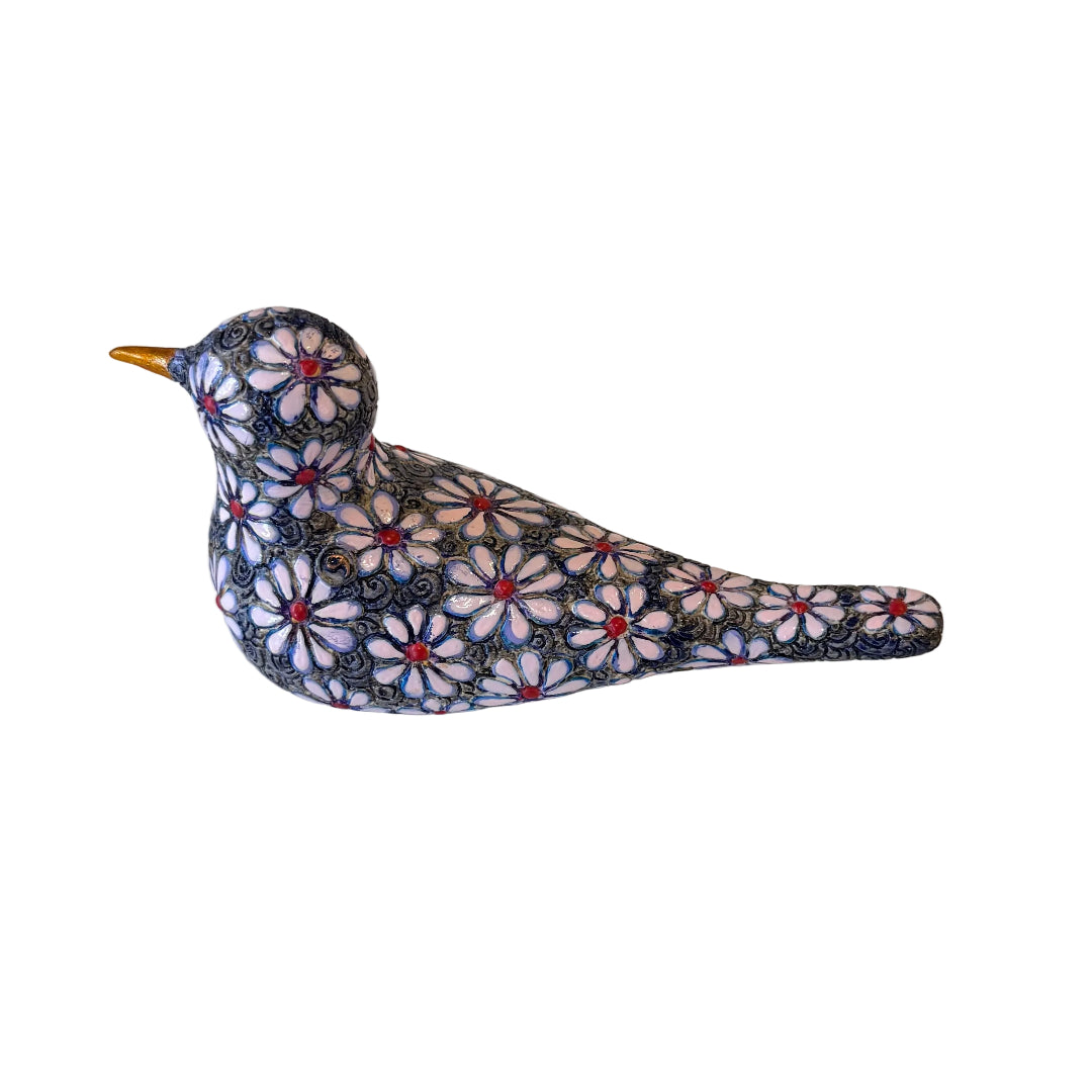 A decorative bird figurine with a detailed floral pattern in navy blue, white, and red, featuring a small gold beak, set against a plain white background.
