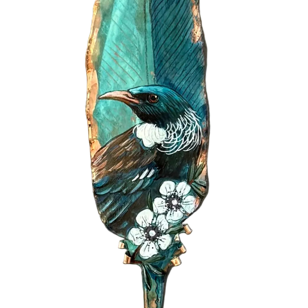 Close up view of a copper feather wall art hand painted with a Tui bird on Manuka flowers against a white background.