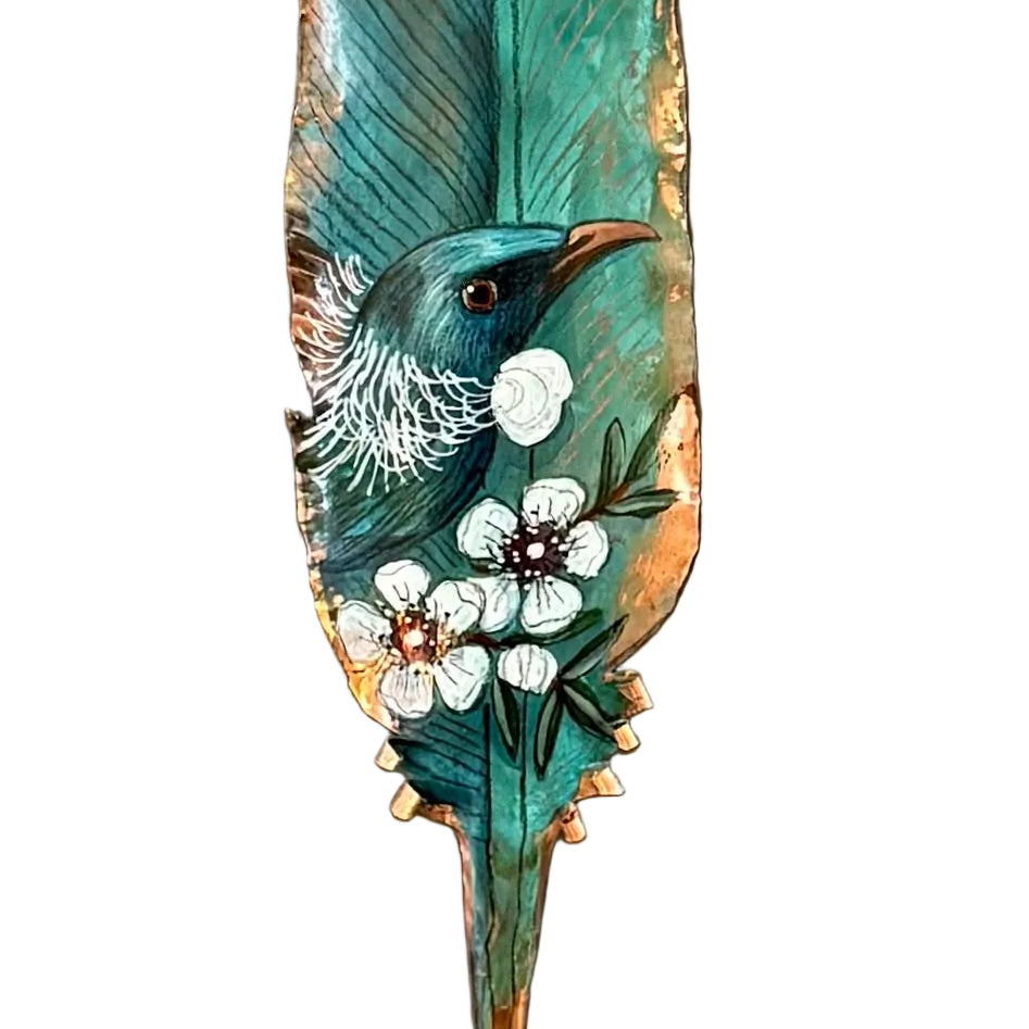 Close up view of a copper feather wall art hand painted with a Tui bird on Manuka flowers against a white background.