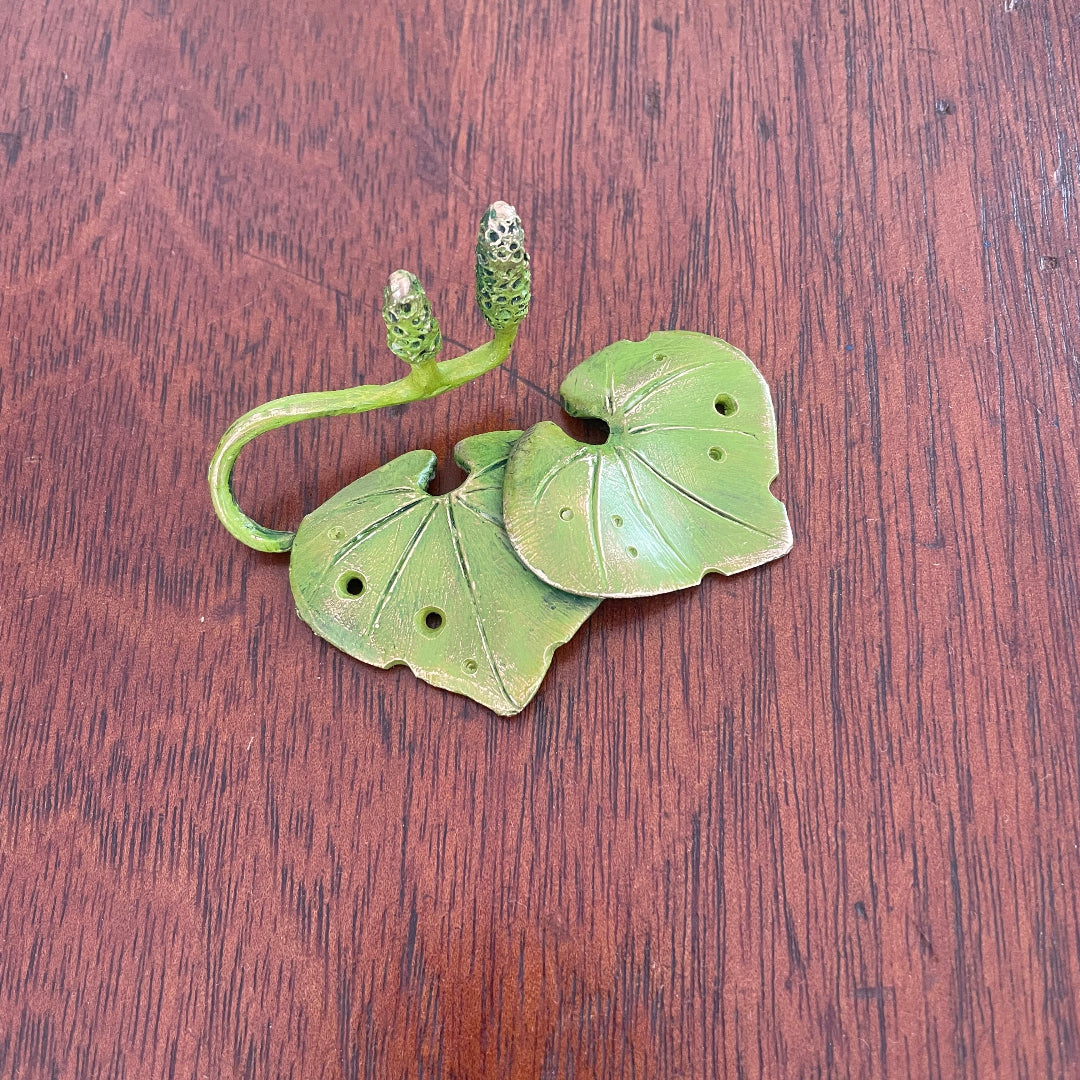 Painted Kawakawa Leaves bronze miniature sulpture on a wooden table.