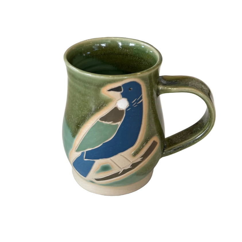 Green ceramic mug with a tui bird design on a white surface