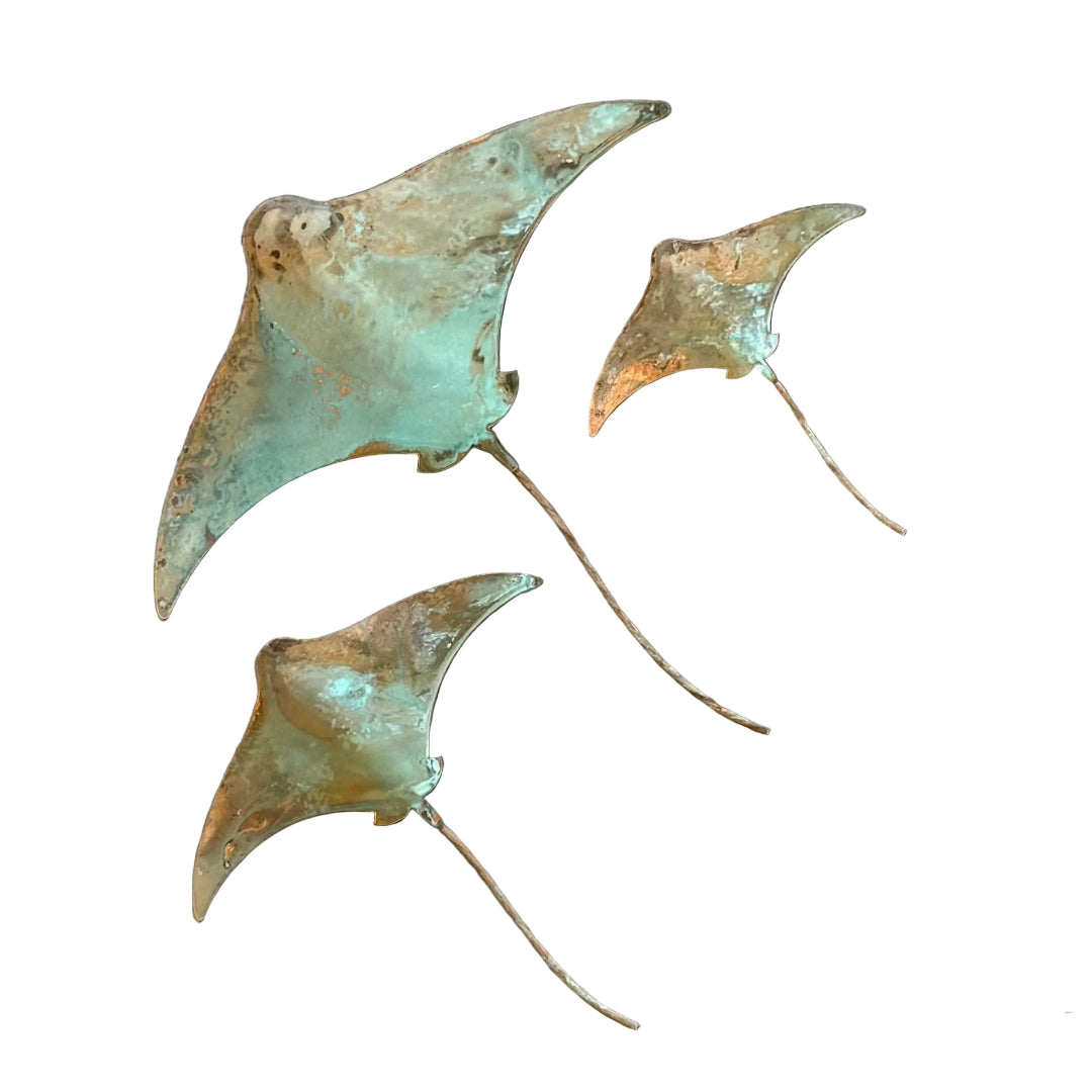 Three patina'd copper stingray wall sculptures on a white background