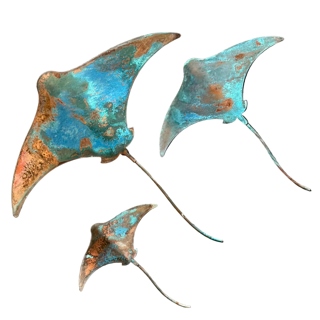 Three patina'd copper stingray wall sculptures on a white background