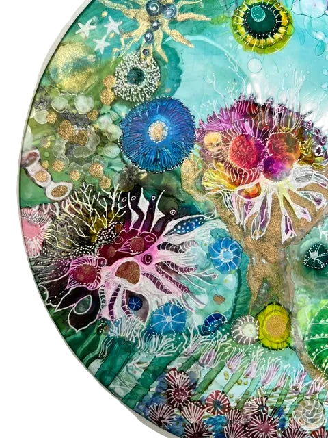Colorful underwater scene with sea creatures and coral on a circular piece of art.