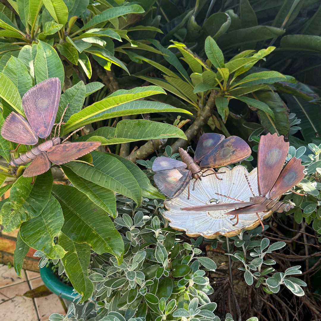 Copper moth sculptures on a leafy plant