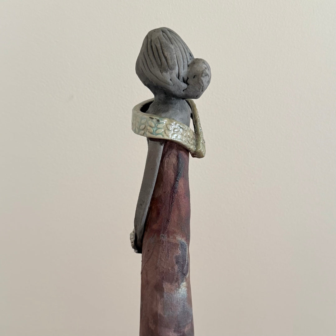 Decorative ceramic sculpture of a woman on a plain background