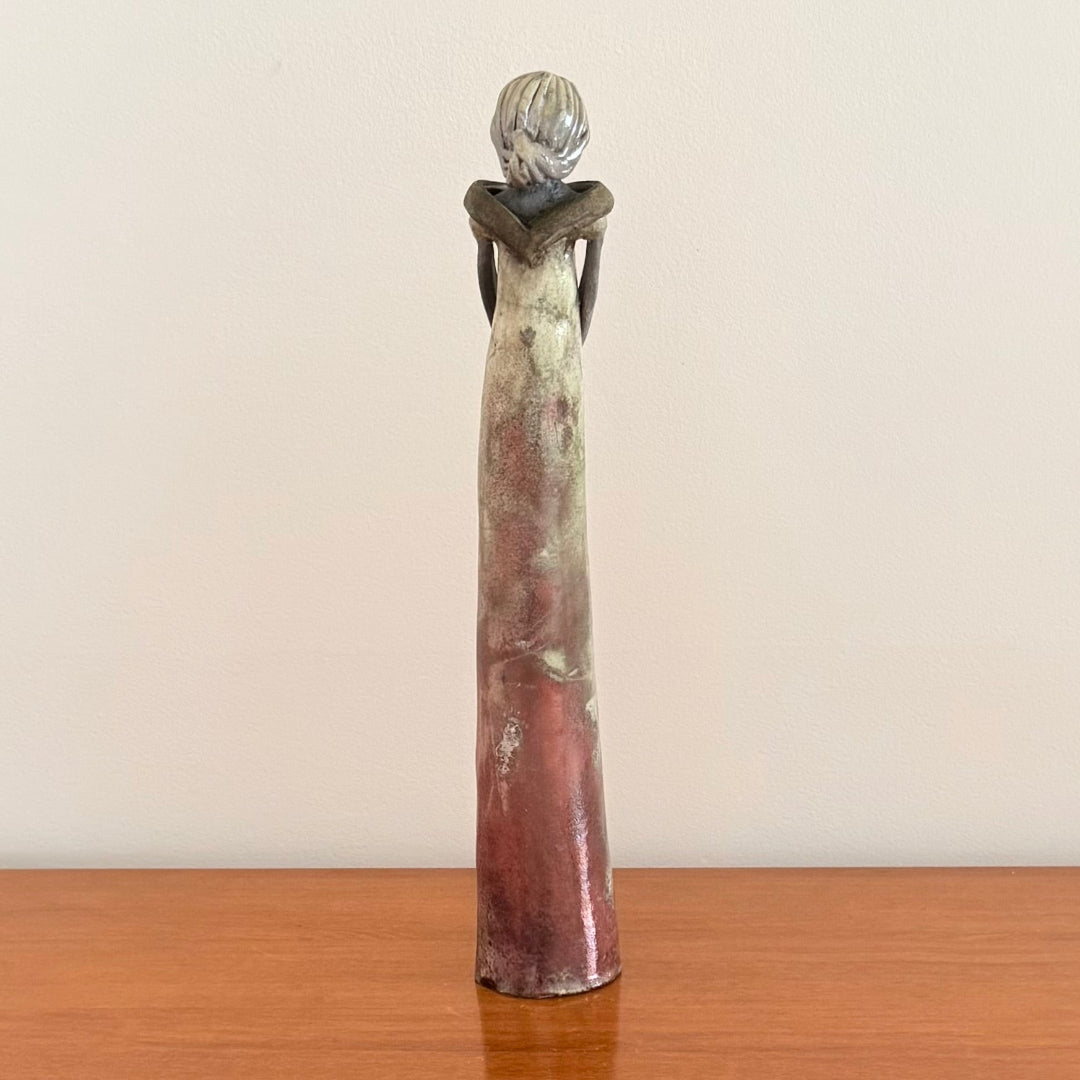 Decorative ceramic sculpture of a woman on a plain background