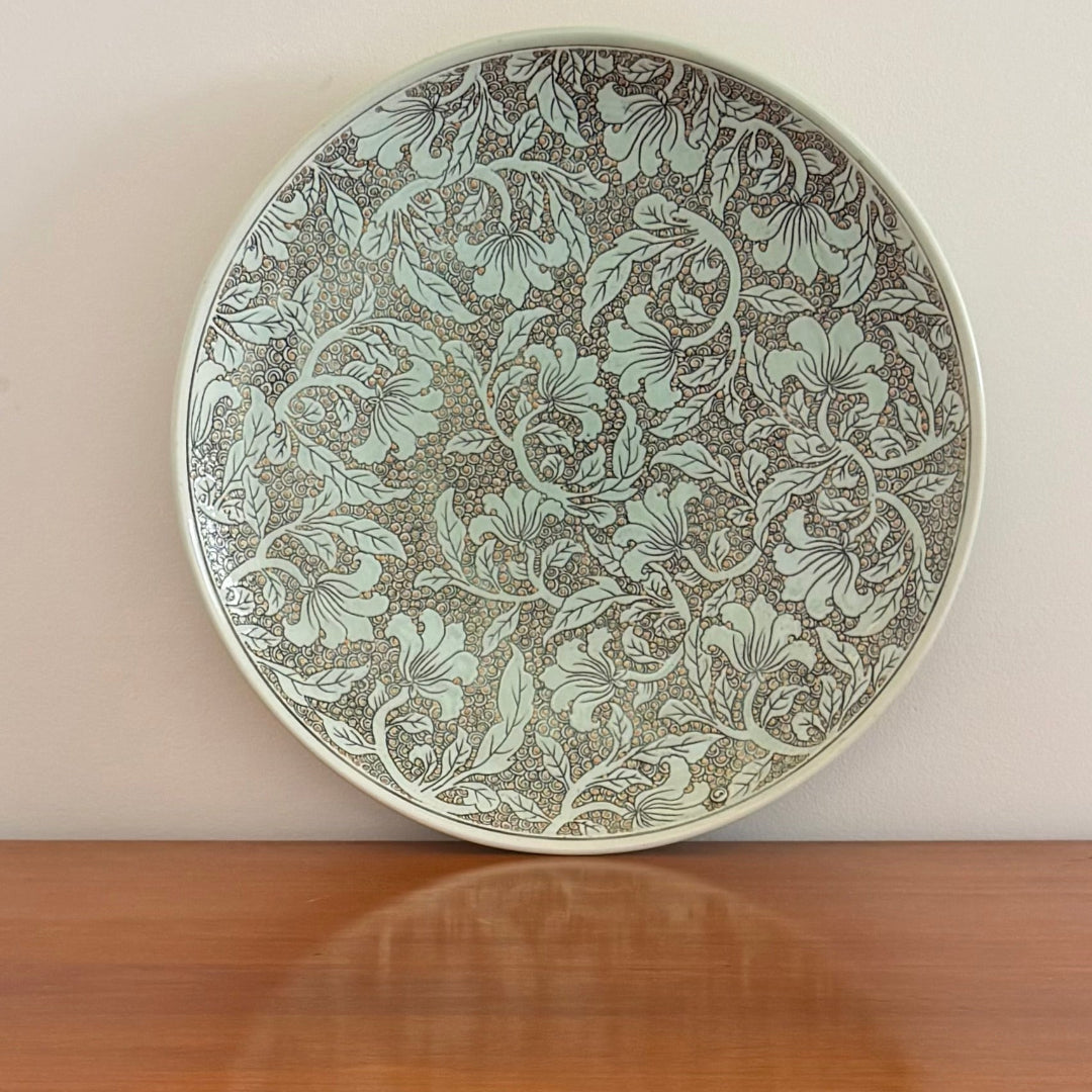 Decorative plate with floral pattern on a wooden surface and beige wall background