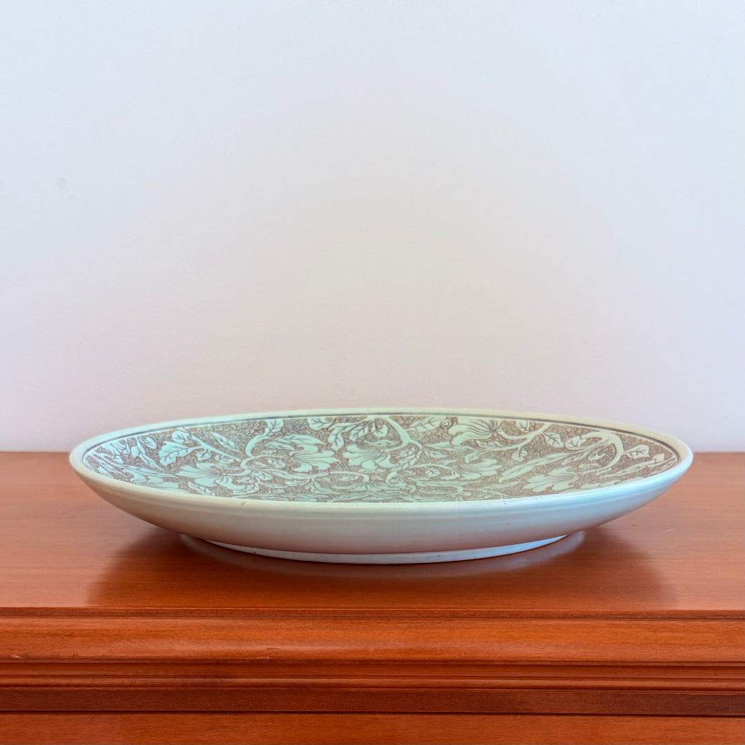 Decorative plate with green pattern on a wooden surface
