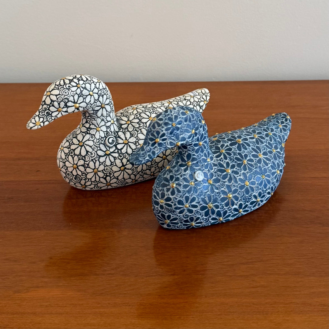 Two fabric ducks with floral patterns on a wooden surface
