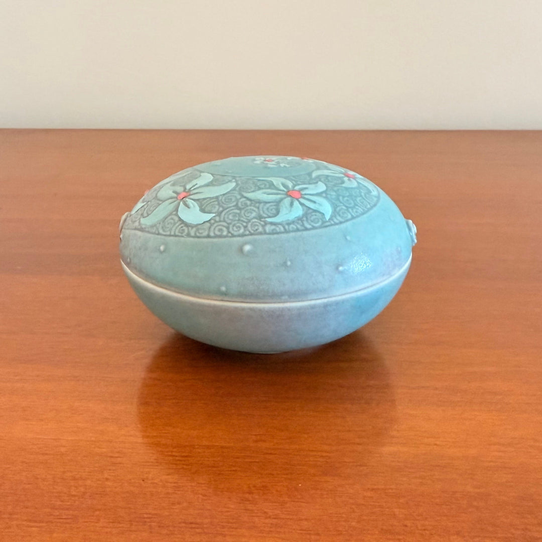 Decorative ceramic bowl with lid with floral patterns on a wooden surface