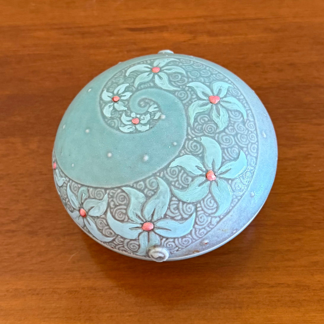 Decorative round jewellery dish with intricate patterns on a wooden surface