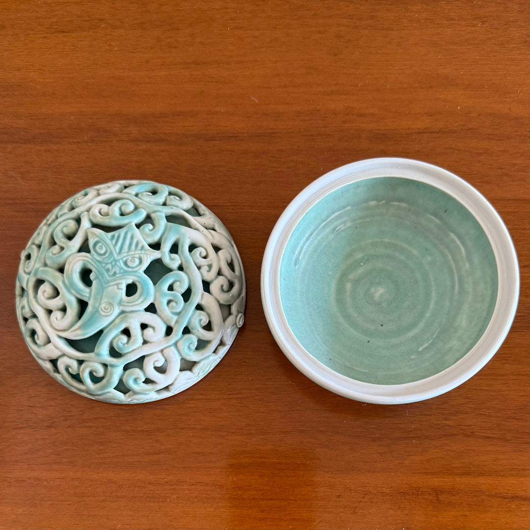 Ceramic lid & bowl with intricate design on a wooden surface