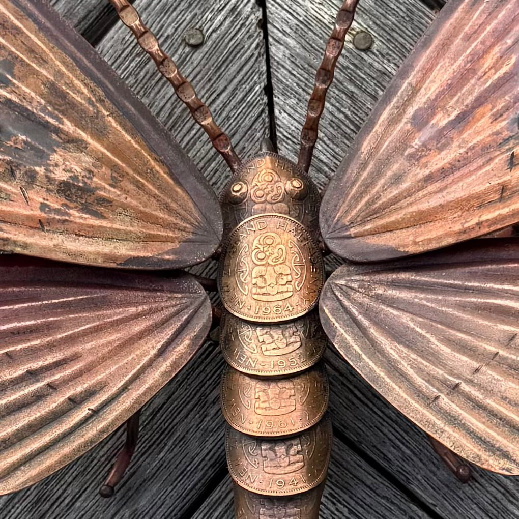 Copper moth sculpture with detailed wings on a wooden surface