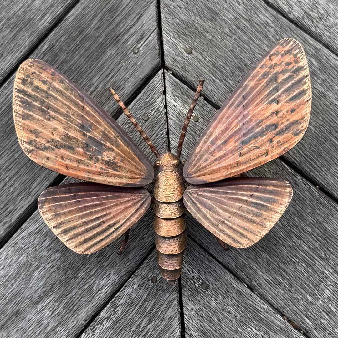 Copper moth sculpture on a wooden surface
