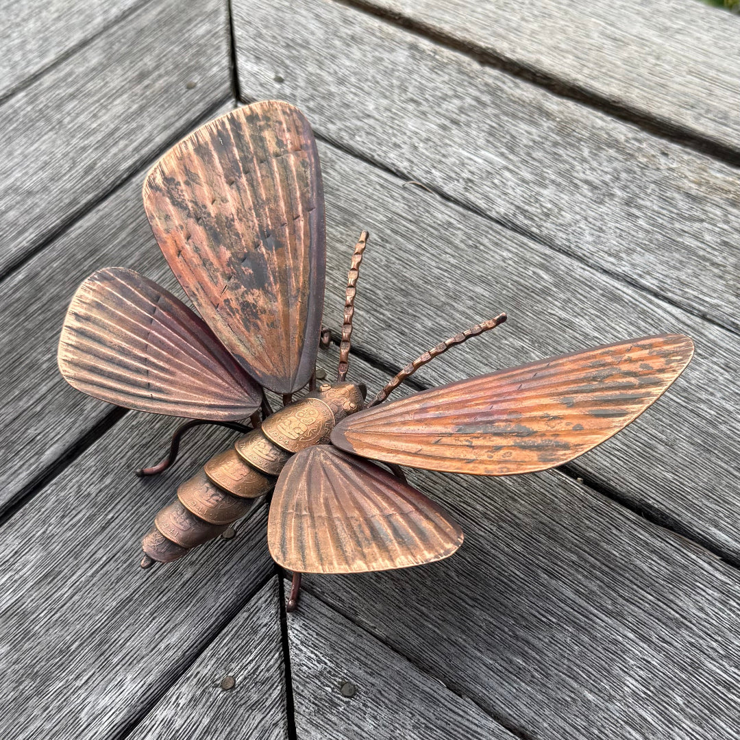 Copper moth sculpture on a wooden surface