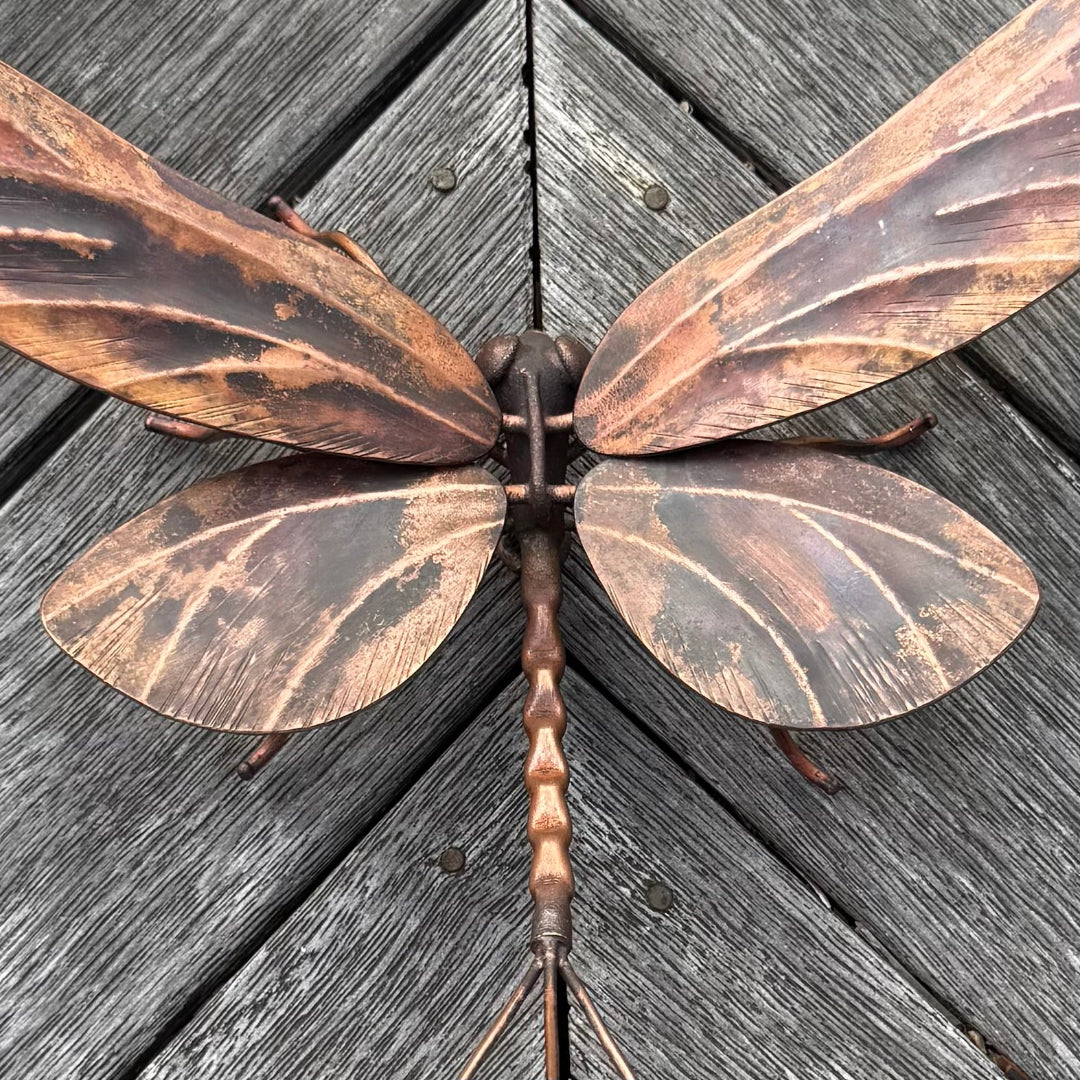 Decorative copper mayfly on a wooden surface