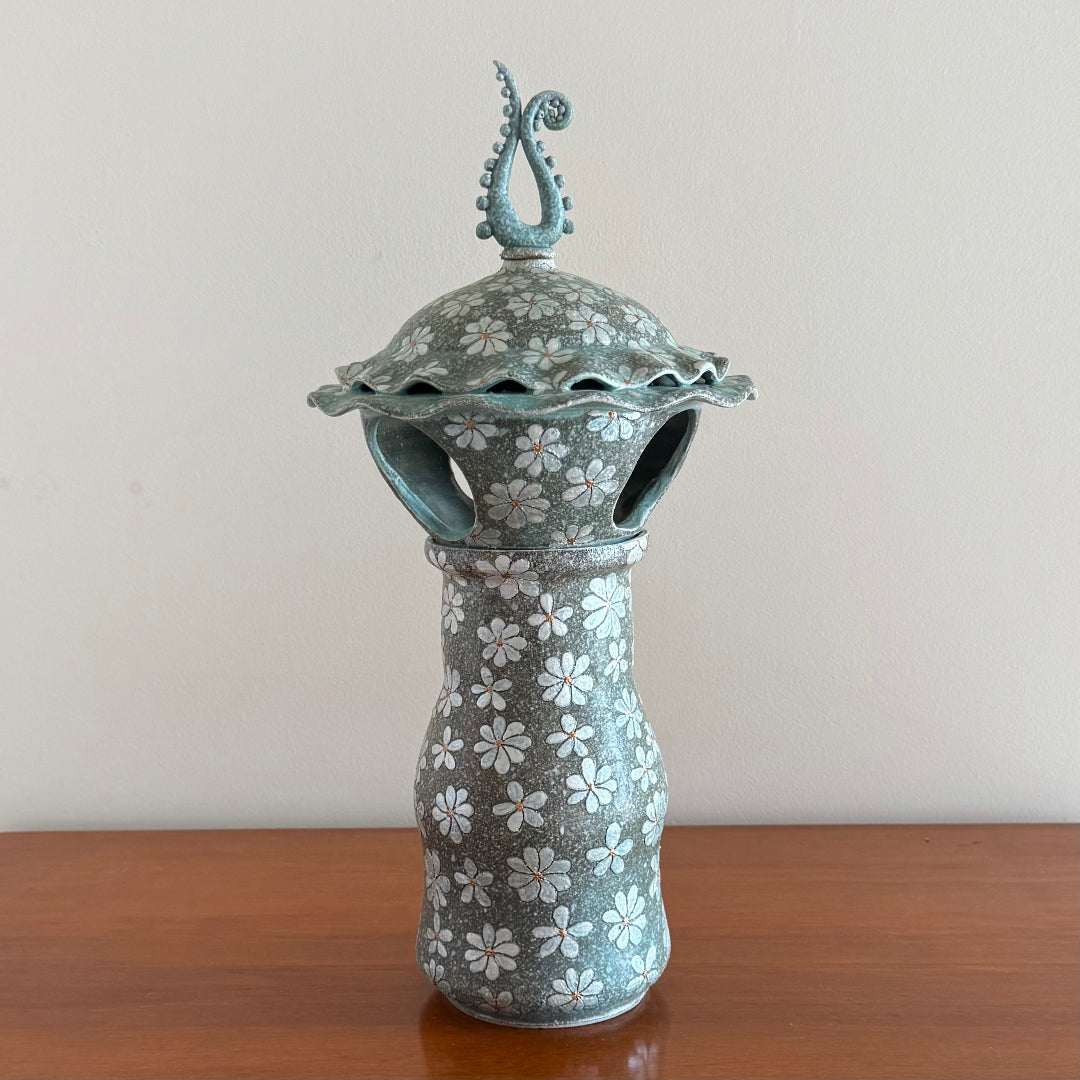3 Piece ceramic Lantern including the base, lantern , and finial on a wooden surface.