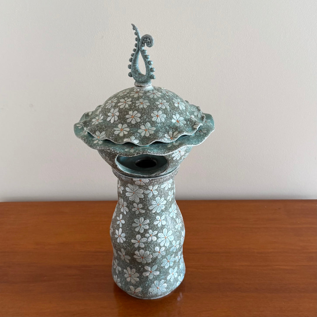 3 Piece ceramic Lantern including the base, lantern , and finial on a wooden surface.