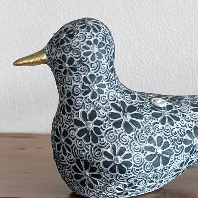 Decorative bird figurine with floral patterns on a wooden surface