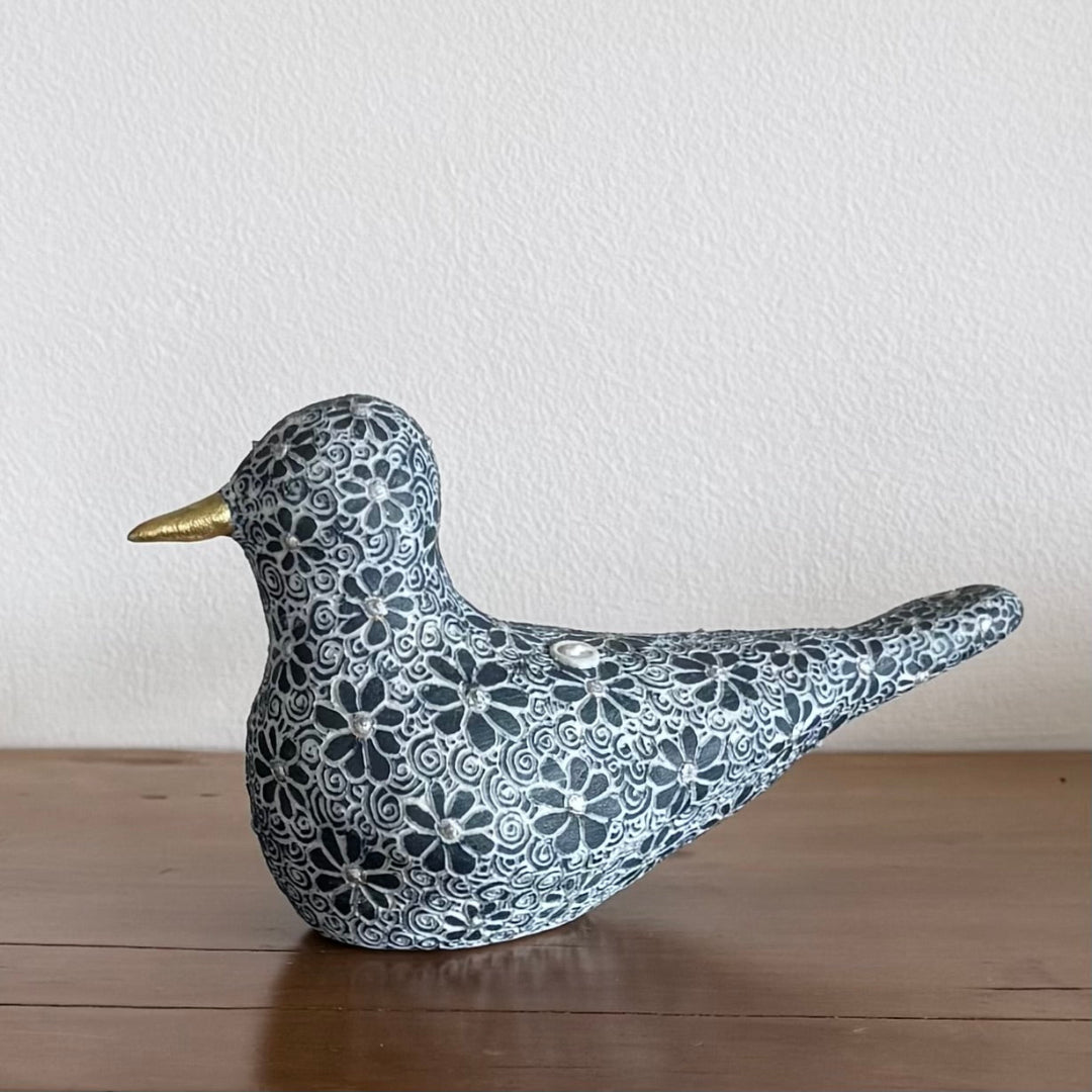 Decorative bird figurine with floral patterns on a wooden surface