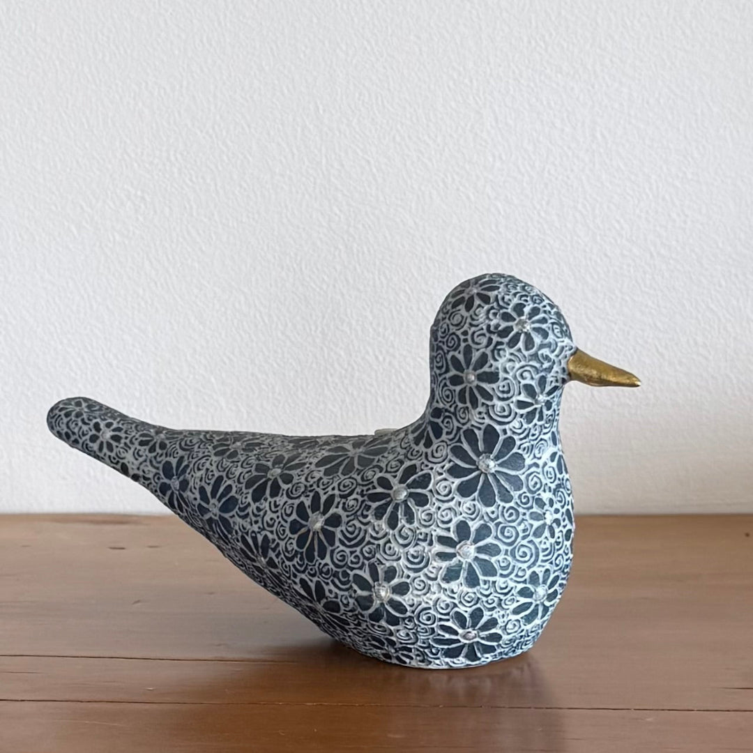 Decorative ceramic bird figurine witha Daisy pattern on a wooden surface