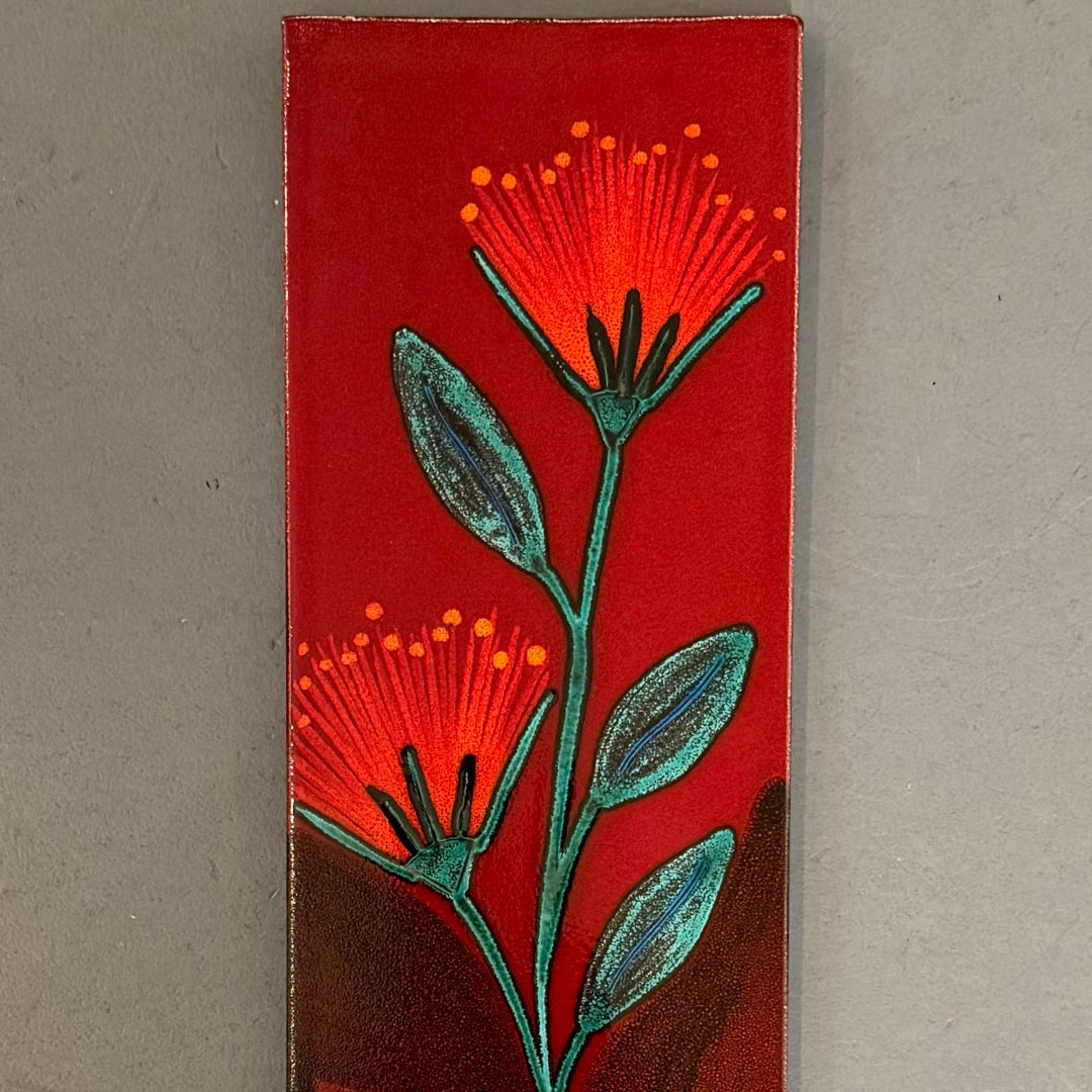 Rectangular ceramic tile with a red pohutakawa design on a grey background