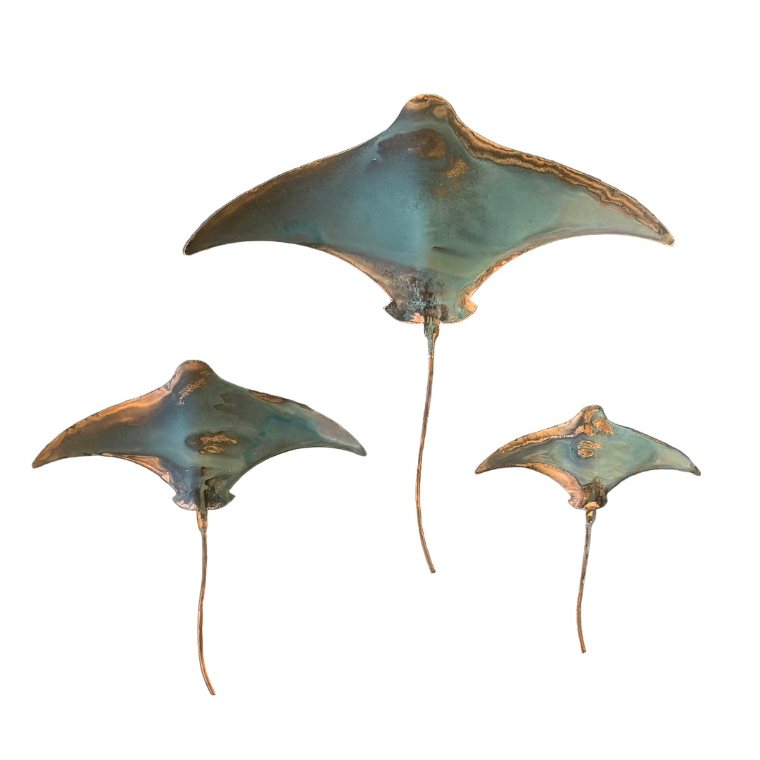 Three stingrays made of copper on a white background