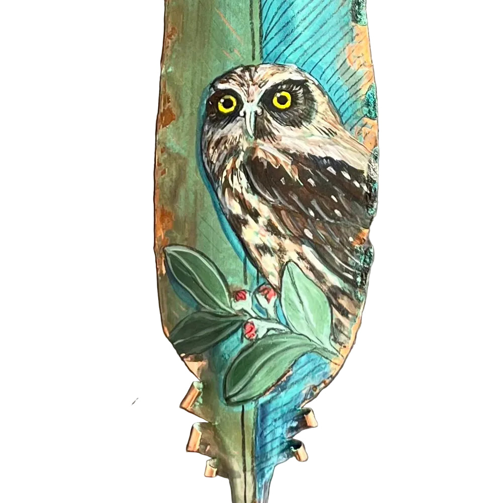 Decorative copper feather with an owl design on a white background