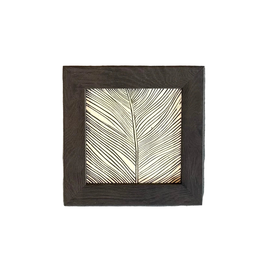 Square framed tile with a feather pattern on a white surface