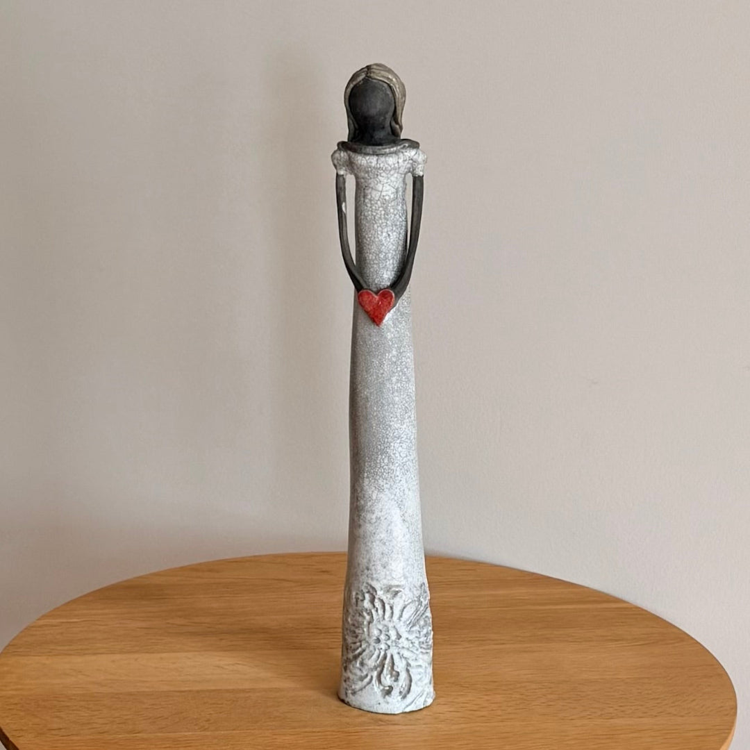 Decorative black clay lady statue with a textured design on a wooden surface