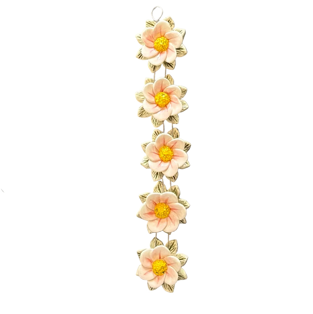 Decorative wall hanging with pink ceramic flowers on a white background
