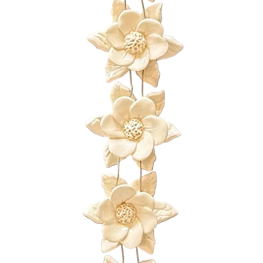 Close up of 3 centre ceramic flowers from a decorative string of 5 white flowers against a white background