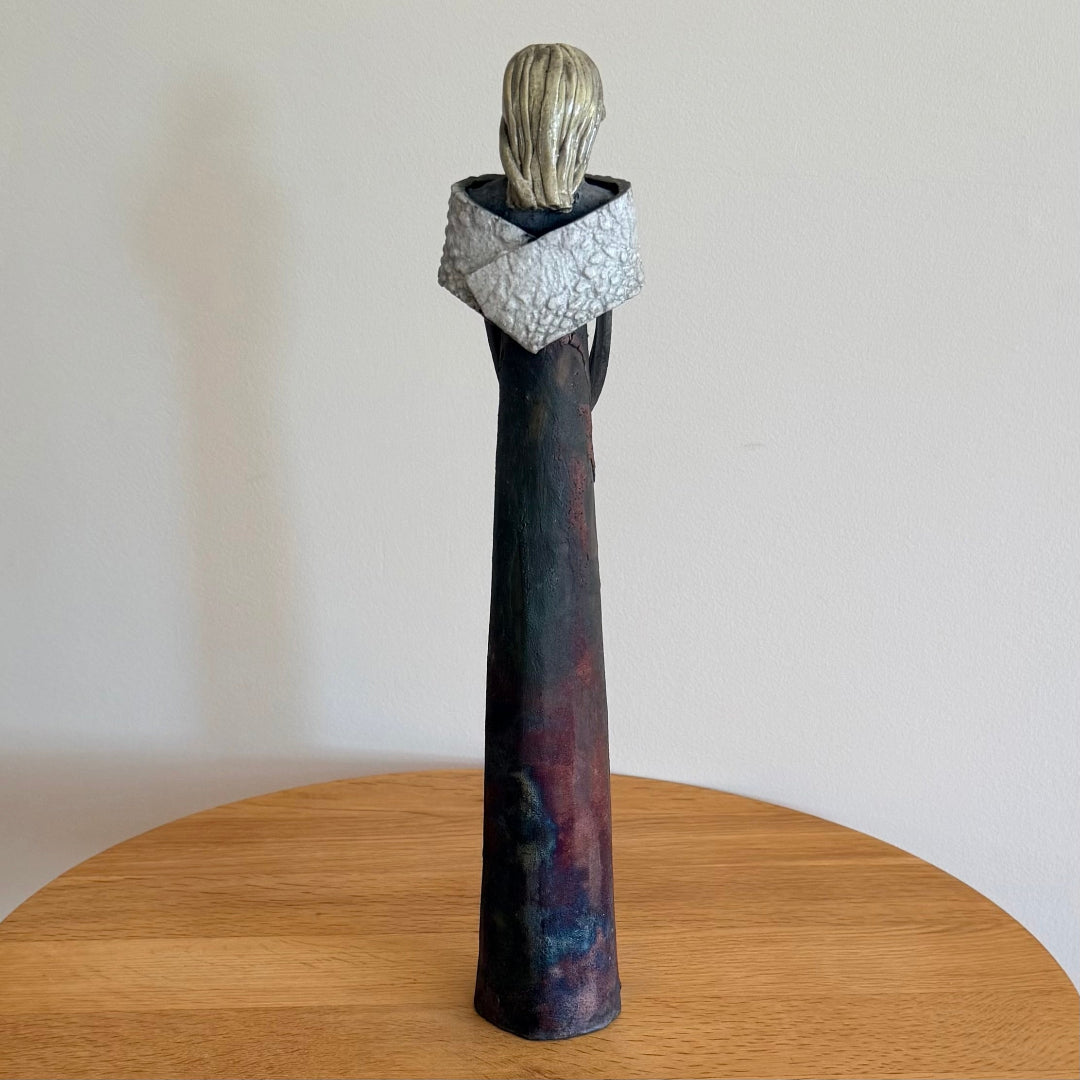 Back view of a ceramic lady with a matt finish on a wooden table
