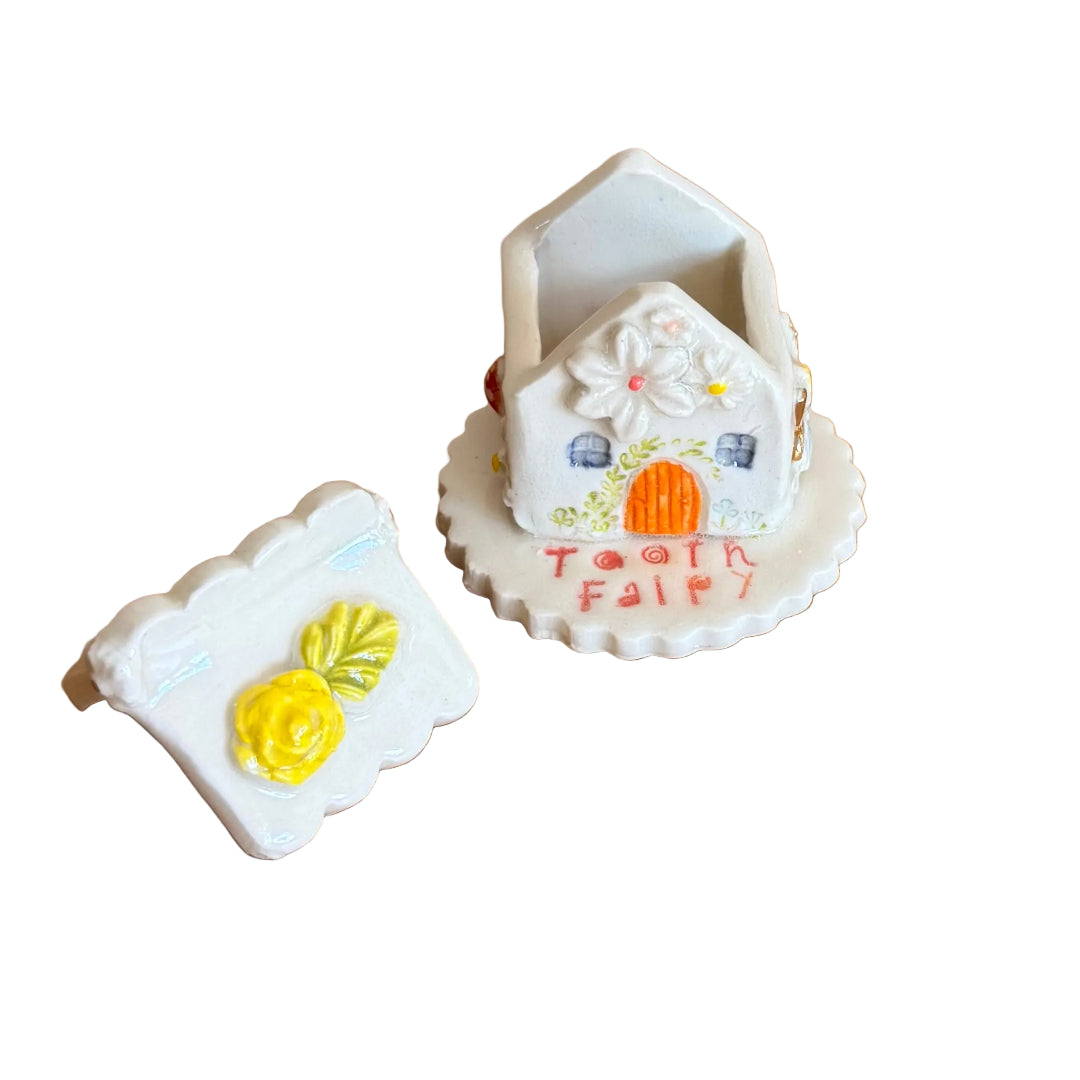 Decorative ceramic trinket box small house with 'Tooth Fairy' text on a white surface