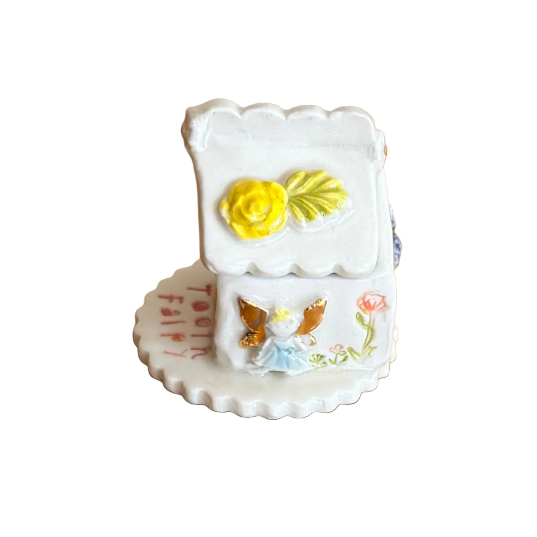 Decorative ceramic trinket box small house with 'Tooth Fairy' text on a white surface