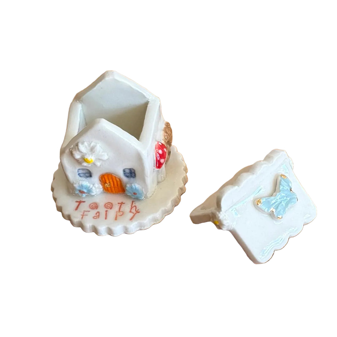 Decorative ceramic trinket box small house with 'Tooth Fairy' text on a white surface