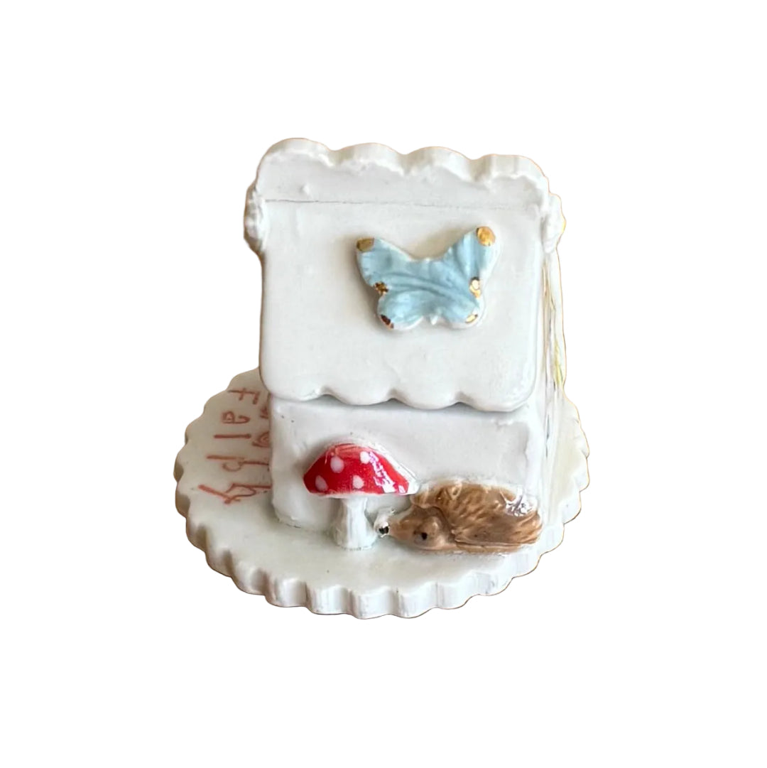 Decorative ceramic trinket box small house with 'Tooth Fairy' text on a white surface