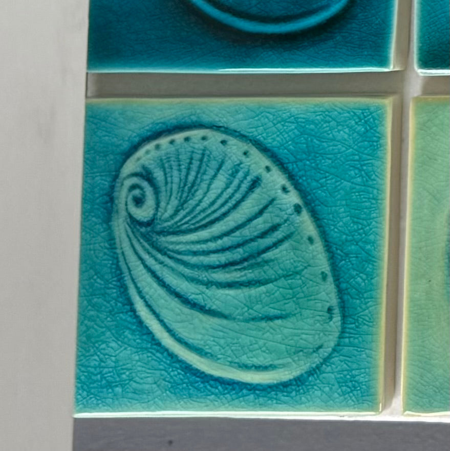 Turquoise ceramic tile with paua shell design on a white background