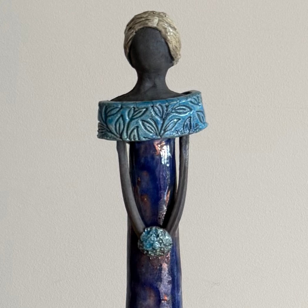 Decorative figurine with blue and black design on a plain background