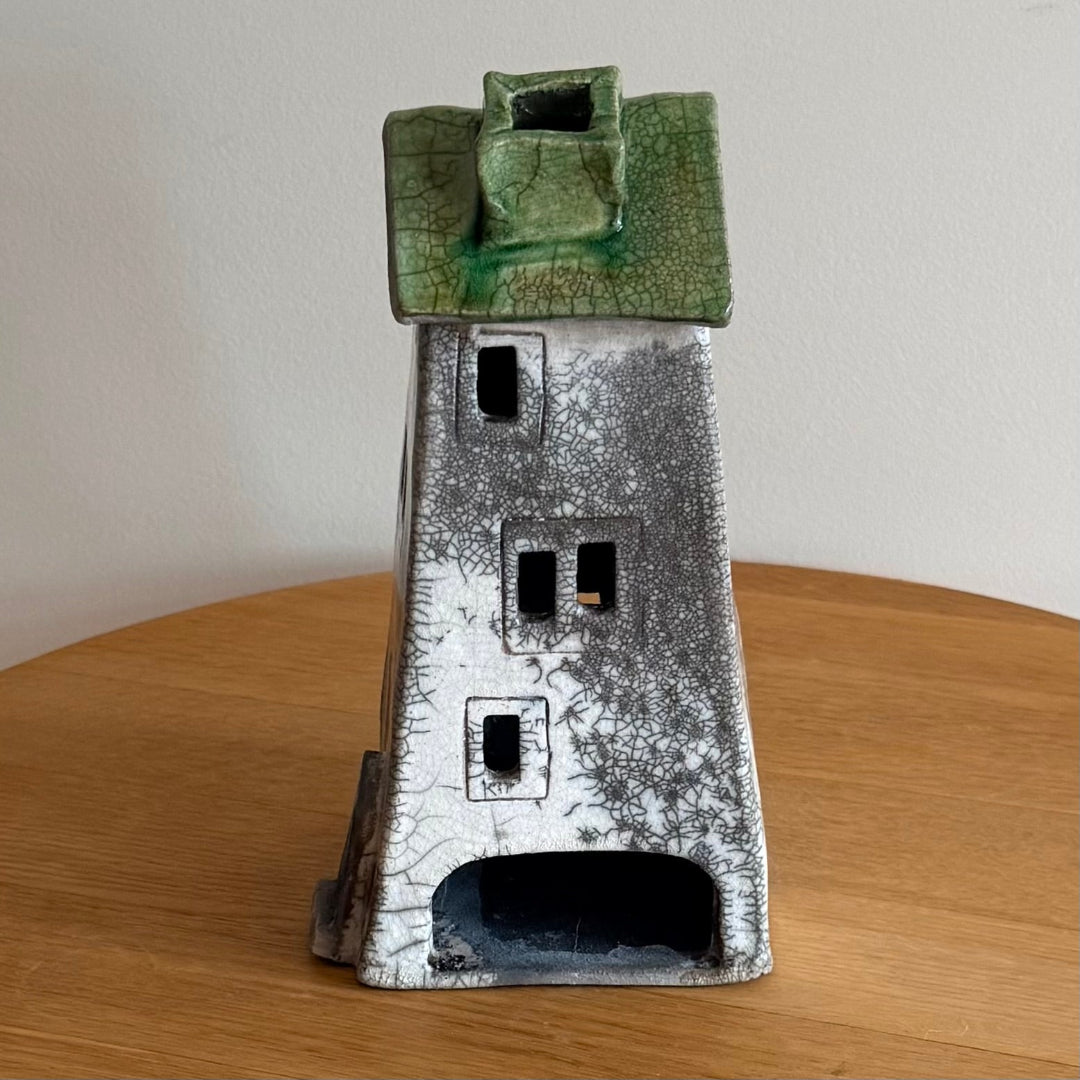 Ceramic tall tealight house with green roof on a wooden surface