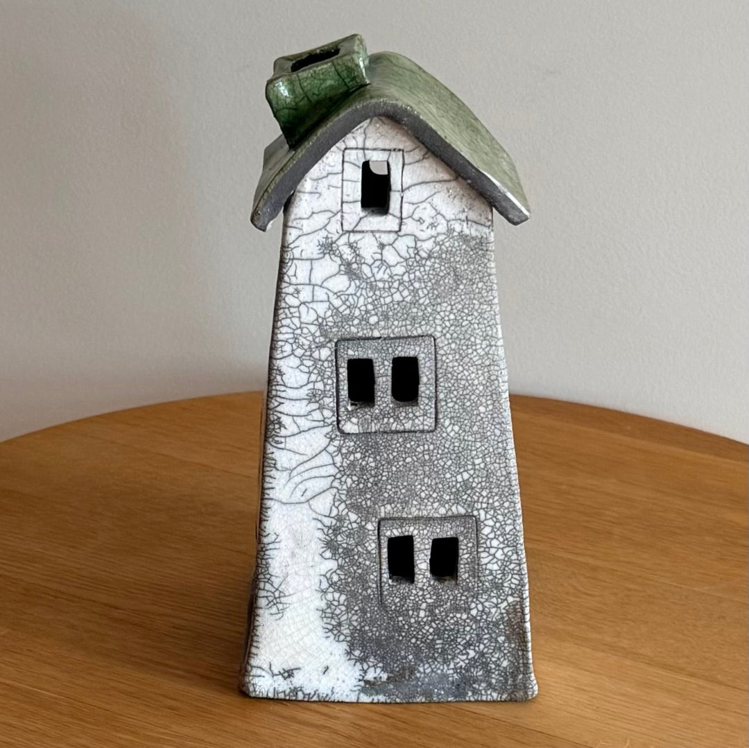 Ceramic tall tealight house with a textured surface on a wooden surface